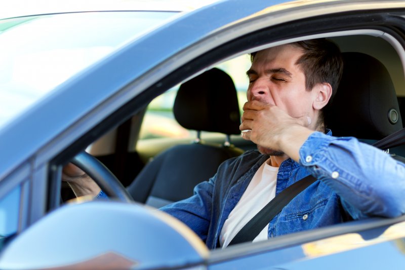 Man yawns in car