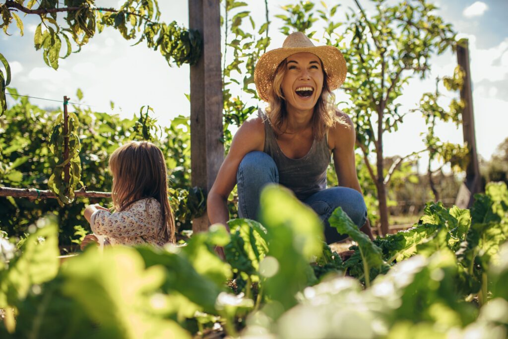 Little girl and woman in straw hat outside gardening